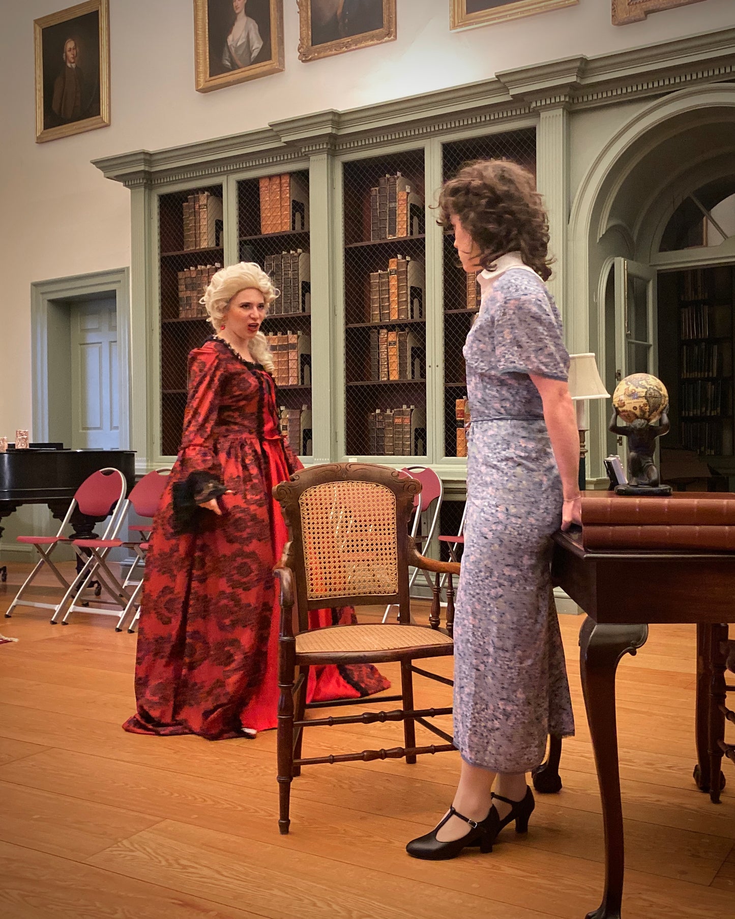 Cast of Valkyrie Productions' Pay No Heed in vintage attire in Redwood Library with bookshelves and a desk.